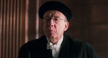 Movie still from “Invincible” (2001), directed by Werner Herzog – An older man wearing a hat and glasses; Close Up shot, Over the shoulder angle