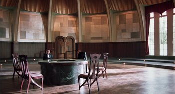 Movie still from “Invincible” (2001), directed by Werner Herzog – A man sitting at a table in front of a fireplace; Extreme Wide shot, High angle