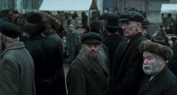 Movie still from “Invincible” (2001), directed by Werner Herzog – A group of men in hats and coats standing next to each other; Medium shot, Over the shoulder angle