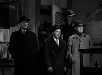 Movie still from “Invisible Agent” (1942), directed by Edwin L. Marin – A black and white photo of a group of men wearing hats and coats; Medium shot, Low angle