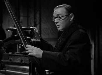 Movie still from “Invisible Agent” (1942), directed by Edwin L. Marin – An older man wearing glasses is holding a piano; Medium shot, Low angle