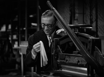 Movie still from “Invisible Agent” (1942), directed by Edwin L. Marin – A black and white photo of a man in a suit and tie; Medium shot, Low angle