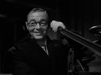 Movie still from “Invisible Agent” (1942), directed by Edwin L. Marin – An older man wearing glasses and a jacket; Close Up shot, Low angle