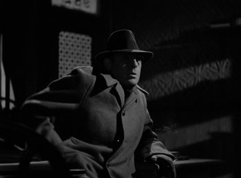 Movie still from “Invisible Agent” (1942), directed by Edwin L. Marin – A black and white photo of a man wearing a hat; Medium shot, Low angle