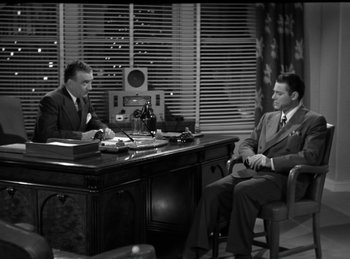 Movie still from “Invisible Agent” (1942), directed by Edwin L. Marin – Two men sitting at a desk in front of each other; Wide shot, High angle