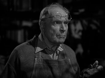 Movie still from “Invisible Agent” (1942), directed by Edwin L. Marin – An older man wearing glasses and a apron; Close Up shot, Low angle