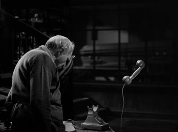 Movie still from “Invisible Agent” (1942), directed by Edwin L. Marin – An older man standing in front of an old phone; Medium shot, High angle