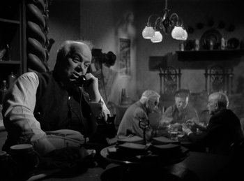 Movie still from “Invisible Agent” (1942), directed by Edwin L. Marin – An older man sitting at a table talking on the phone; Medium shot, High angle