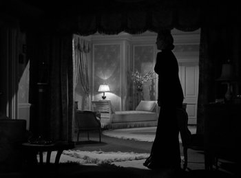 Movie still from “Invisible Agent” (1942), directed by Edwin L. Marin – A black and white photo of a woman walking in front of a bed; Wide shot, Low angle