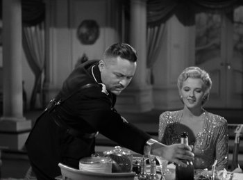 Movie still from “Invisible Agent” (1942), directed by Edwin L. Marin – A man and a woman are sitting at a dinner table; Medium shot, Low angle