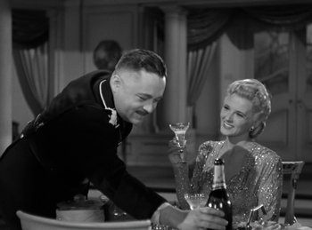 Movie still from “Invisible Agent” (1942), directed by Edwin L. Marin – A man and a woman are drinking champagne; Medium shot, Low angle