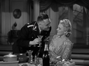 Movie still from “Invisible Agent” (1942), directed by Edwin L. Marin – A man and a woman sitting at a table with a wine glass; Medium shot, High angle