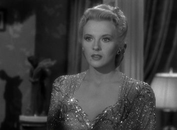 Movie still from “Invisible Agent” (1942), directed by Edwin L. Marin – A black - and - white photo of a woman in a sequined dress; Close Up shot, Over the shoulder angle
