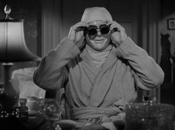 Movie still from “Invisible Agent” (1942), directed by Edwin L. Marin – A man in a robe and sunglasses sitting at a dinner table; Close Up shot, Over the shoulder angle