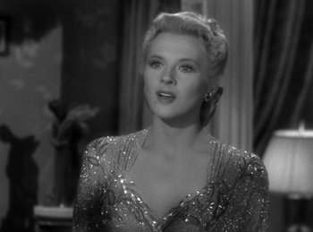 Movie still from “Invisible Agent” (1942), directed by Edwin L. Marin – A black - and - white photo of a woman in a silver dress; Close Up shot, Over the shoulder angle