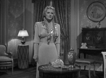 Movie still from “Invisible Agent” (1942), directed by Edwin L. Marin – A black and white photo of a woman standing in front of a cake; Medium shot, Low angle