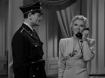 Movie still from “Invisible Agent” (1942), directed by Edwin L. Marin – A man and a woman standing next to each other; Medium shot, Low angle