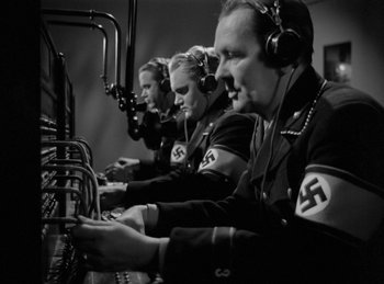 Movie still from “Invisible Agent” (1942), directed by Edwin L. Marin – A black and white photo of a group of men in military uniforms; Medium shot, High angle