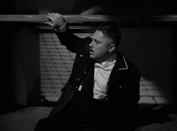 Movie still from “Invisible Agent” (1942), directed by Edwin L. Marin – A black and white photo of a man sitting on a bench; Medium shot, High angle