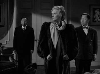 Movie still from “Invisible Agent” (1942), directed by Edwin L. Marin – A black and white photo of a woman in a fur coat; Medium shot, Low angle