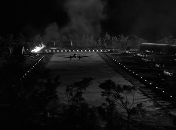 Movie still from “Invisible Agent” (1942), directed by Edwin L. Marin – An airplane is on a runway at night; Extreme Wide shot, High angle