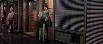 Movie still from “Irma la Douce” (1963), directed by Billy Wilder – A woman dressed in green and holding a stuffed animal; Wide shot, Low angle