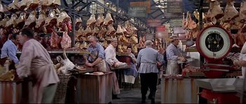 Movie still from “Irma la Douce” (1963), directed by Billy Wilder – A group of people standing around a market; Wide shot, High angle