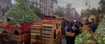 Movie still from “Irma la Douce” (1963), directed by Billy Wilder – A group of people standing next to boxes of fruit; Wide shot, High angle