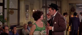 Movie still from “Irma la Douce” (1963), directed by Billy Wilder – A man and a woman talking on a cell phone in front of other people; Medium shot, Low angle