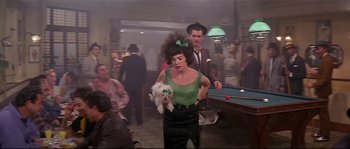Movie still from “Irma la Douce” (1963), directed by Billy Wilder – A woman holding a white dog in her arms; Medium shot, Over the shoulder angle
