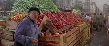 Movie still from “Irma la Douce” (1963), directed by Billy Wilder – A man standing in front of a pile of apples; Medium shot, Low angle