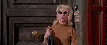 Movie still from “Irma la Douce” (1963), directed by Billy Wilder – A woman with blonde hair blowing a bubble with a bubble wand; Medium shot, Low angle
