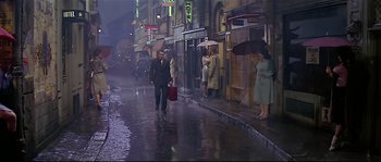 Movie still from “Irma la Douce” (1963), directed by Billy Wilder – A man walking down the street in the pouring rain; Wide shot, High angle