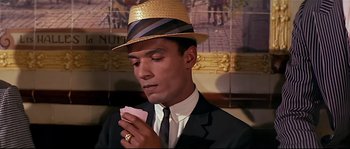 Movie still from “Irma la Douce” (1963), directed by Billy Wilder – A man in a suit and hat holding a card; Close Up shot, High angle