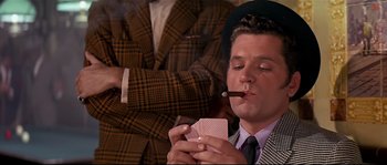 Movie still from “Irma la Douce” (1963), directed by Billy Wilder – A man smoking a cigarette while holding a card; Close Up shot, Over the shoulder angle