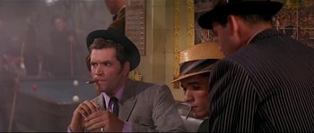 Movie still from “Irma la Douce” (1963), directed by Billy Wilder – A group of men sitting next to each other in a room; Medium shot, Over the shoulder angle