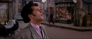 Movie still from “Irma la Douce” (1963), directed by Billy Wilder – A man in a suit and hat looking up at the sky; Close Up shot, Low angle