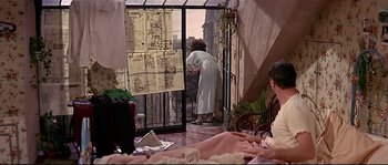 Movie still from “Irma la Douce” (1963), directed by Billy Wilder – A woman in a white robe standing next to a window; Wide shot, High angle