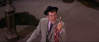 Movie still from “Irma la Douce” (1963), directed by Billy Wilder – A man wearing a suit and tie holding a toothbrush; Close Up shot, Low angle