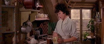 Movie still from “Irma la Douce” (1963), directed by Billy Wilder – A woman in an old - fashioned kitchen preparing a meal; Medium shot, Low angle