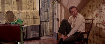 Movie still from “Irma la Douce” (1963), directed by Billy Wilder – A man sitting on the ground in front of an open door; Medium shot, Low angle