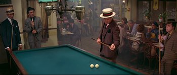 Movie still from “Irma la Douce” (1963), directed by Billy Wilder – A man wearing a hat and a suit playing pool; Medium shot, High angle