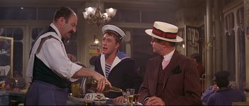 Movie still from “Irma la Douce” (1963), directed by Billy Wilder – A group of men sitting at a table with drinks; Medium shot, Low angle