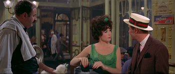 Movie still from “Irma la Douce” (1963), directed by Billy Wilder – A woman in a green dress sitting in front of a building; Medium shot, Over the shoulder angle