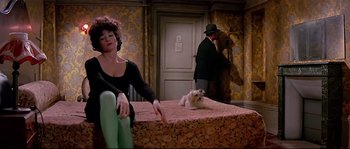 Movie still from “Irma la Douce” (1963), directed by Billy Wilder – A woman sitting on top of a bed next to a white dog; Wide shot, High angle