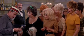 Movie still from “Irma la Douce” (1963), directed by Billy Wilder – A group of women standing next to each other with a dog; Medium shot, Low angle