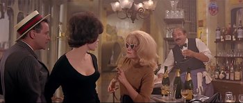 Movie still from “Irma la Douce” (1963), directed by Billy Wilder – Two women are talking at a bar; Medium shot, Over the shoulder angle