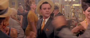 Movie still from “Irma la Douce” (1963), directed by Billy Wilder – A man in a suit and straw hat in a crowd of people; Close Up shot, Over the shoulder angle