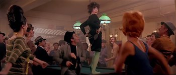 A man and a woman are dancing on a pool table