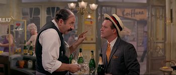 Movie still from “Irma la Douce” (1963), directed by Billy Wilder – Two men in suits and hats are sitting at a table with champagne; Medium shot, Over the shoulder angle